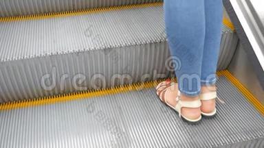 一个穿牛仔裤，穿夏季鞋，凉鞋的女人的腿在一个移动的扶梯上。